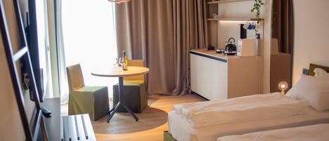 Ein Hotelzimmer mit zwei Betten, einem Schreibtisch, einem Stuhl, einem kleinen Tisch, einem Fernseher und einem Spiegel.