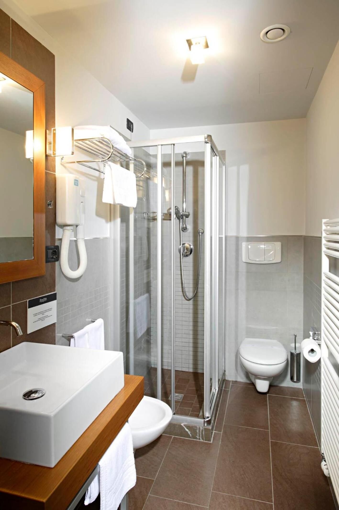 A modern bathroom with a glass-enclosed shower, a white sink, and a toilet.