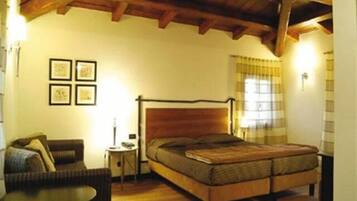 Un dormitorio con una cama de madera, una mesita redonda pequeña, un sofá y una pared decorada con marcos.