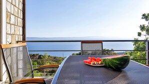 Ein Balkon mit Tisch, Stühlen und einer Wassermelone.