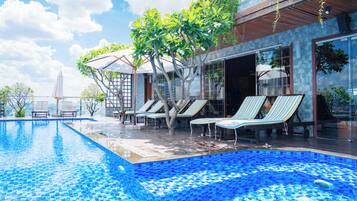 A swimming pool with lounge chairs and a covered area.