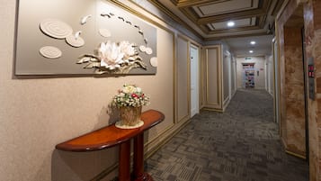 A hallway with a decorative wall, a wooden console table with a floral arrangement, and patterned carpet.