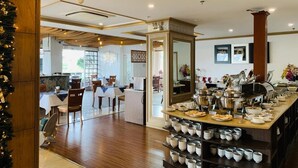 Comedor de hotel con barra de autoservicio, suelo de madera y un espejo grande.