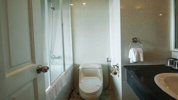 A bathroom with a toilet, a shower, and a sink.
