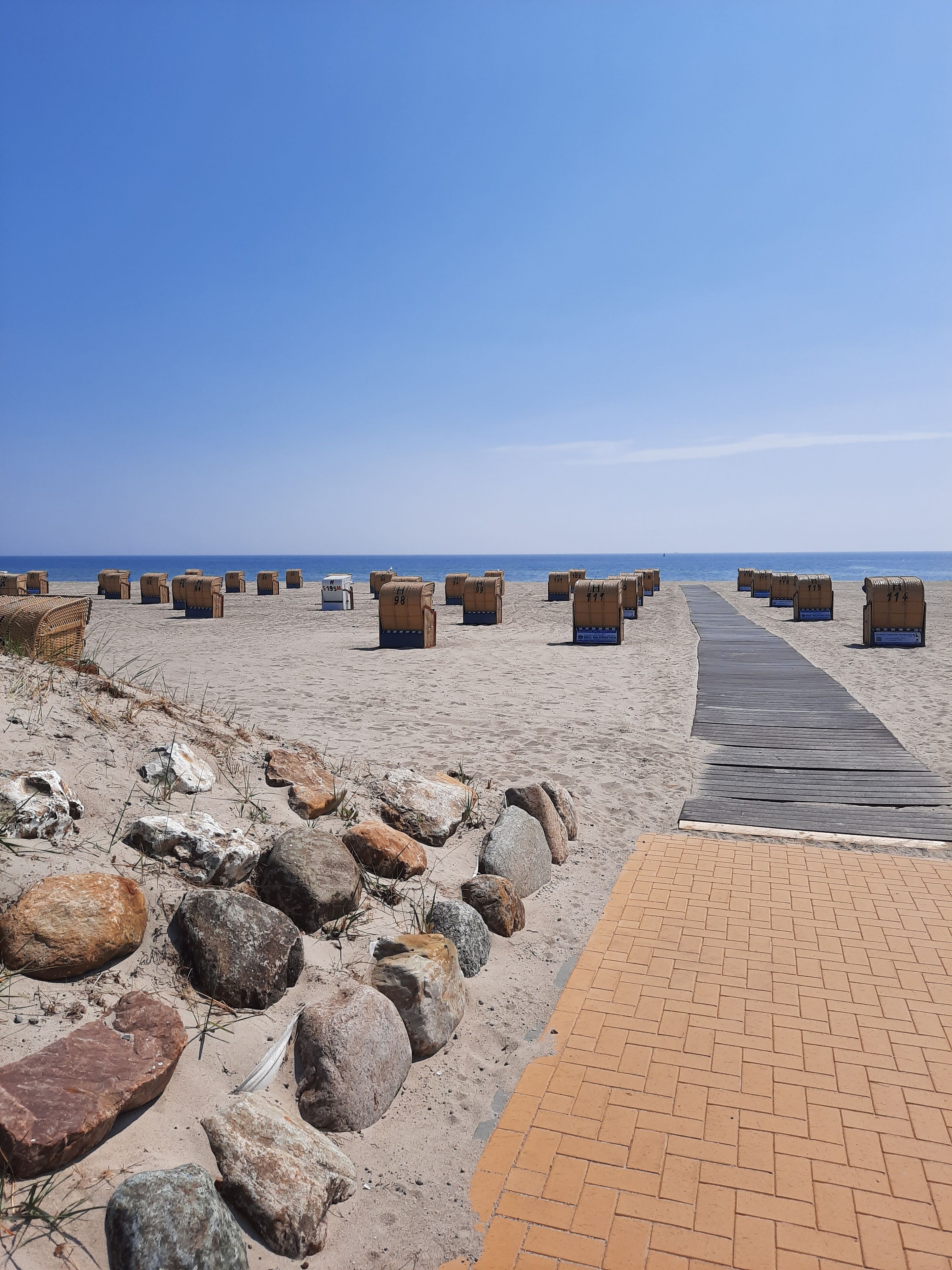 A beach with wooden benches and a brick pathway.