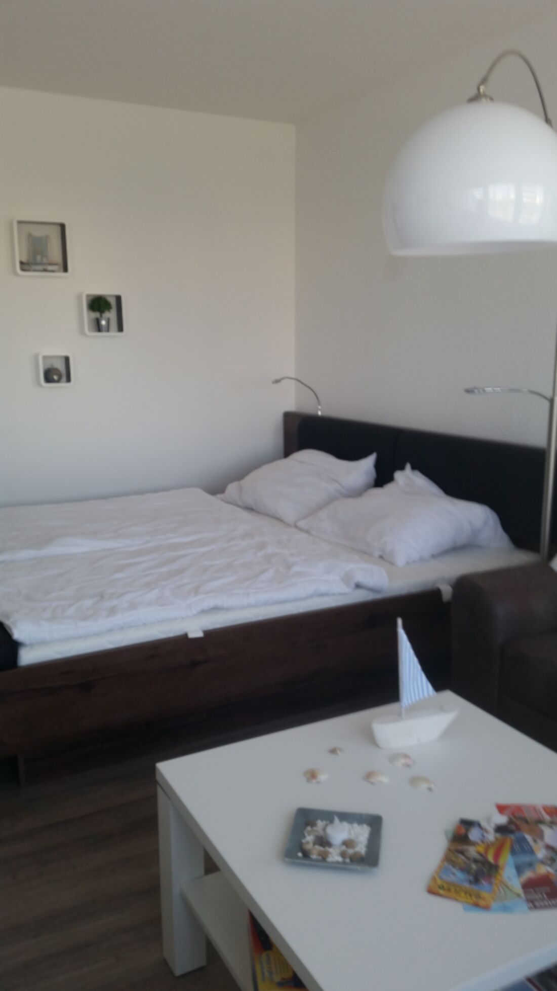 Et soveværelse med seng, natbord, lampe og billeder på væggen.