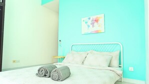 A neatly made bed with a white comforter and two rolled gray towels. - Marc A-30-06 by SYNC (Kuala Lumpur)