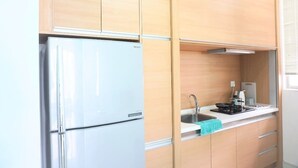 A compact kitchen with a white refrigerator, a sink, and a stove. - Marc A-30-06 by SYNC (Kuala Lumpur)