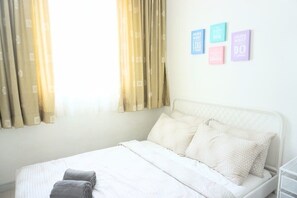 A neatly made bed with white bedding and two rolled towels, a white headboard, and a wall with four motivational posters. - Marc A-30-06 by SYNC (Kuala Lumpur)