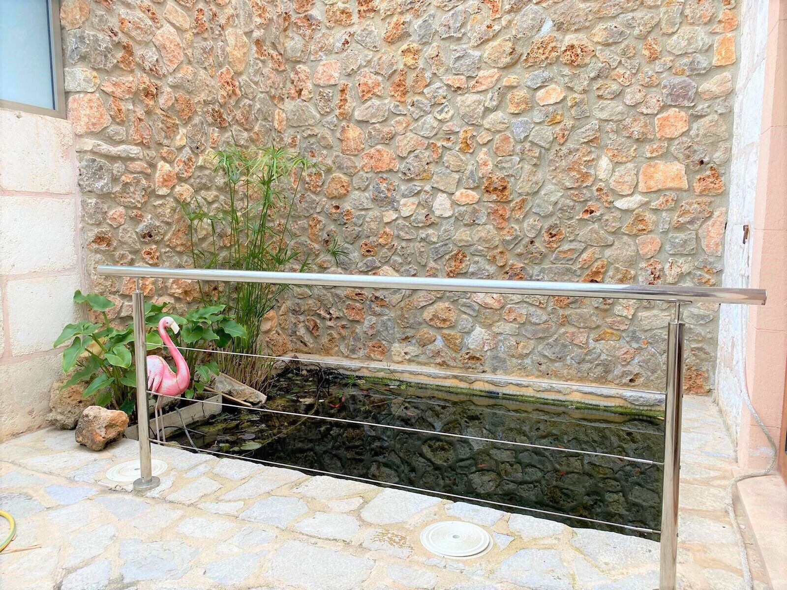 Eine Steinmauer mit Metallgeländer und einem kleinen Wasserspiel.