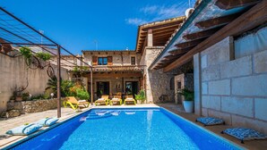 Una piscina con sillas de descanso y un edificio de piedra al fondo.