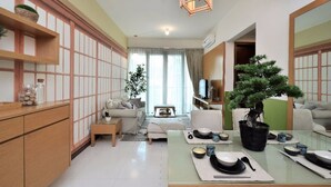 A modern living room with a low table set for dining, a sofa, and a large potted tree. - Marc A-23-09 by SYNC (Kuala Lumpur)
