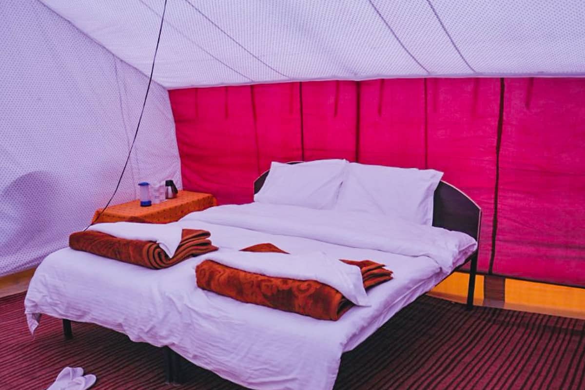 Een hotelkamer met een bed, een nachtkastje en een rode vloerbedekking.