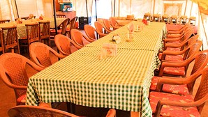 A large dining area with checkered tablecloths and wooden chairs. Tables are arranged in rows, and there are some items on the tables. - Tsomoriri Camp And Resort (Leh)