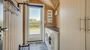 A compact laundry room with a washing machine, a drying rack, and a door leading outside. - Gorgeous home in Sydals with sauna (Sydals)