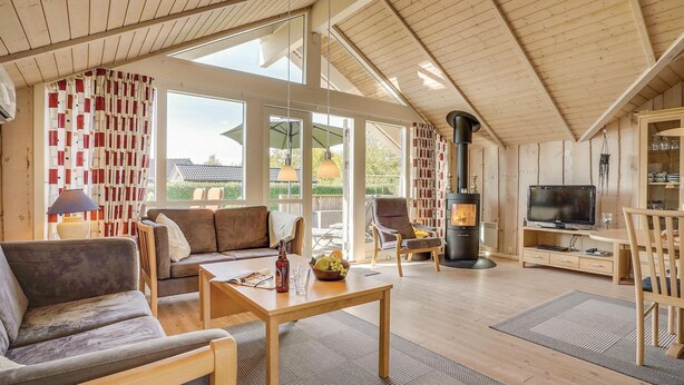 A cozy living room with a sofa, a coffee table, and a television. There is a fireplace and a dining area with chairs. - Gorgeous home in Sydals with sauna (Sydals)