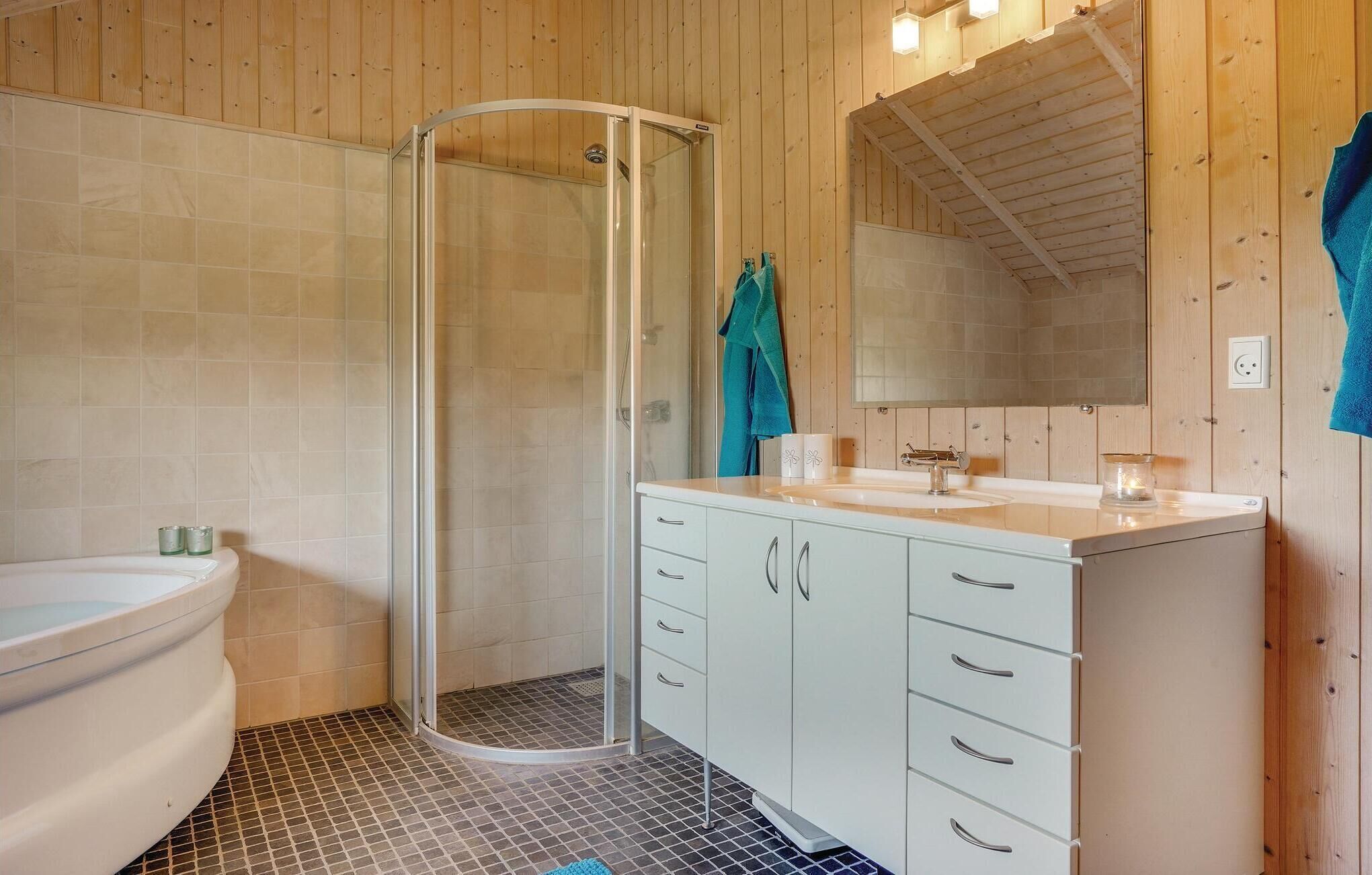 A bathroom with a glass shower enclosure, a white toilet, and a white vanity with drawers.