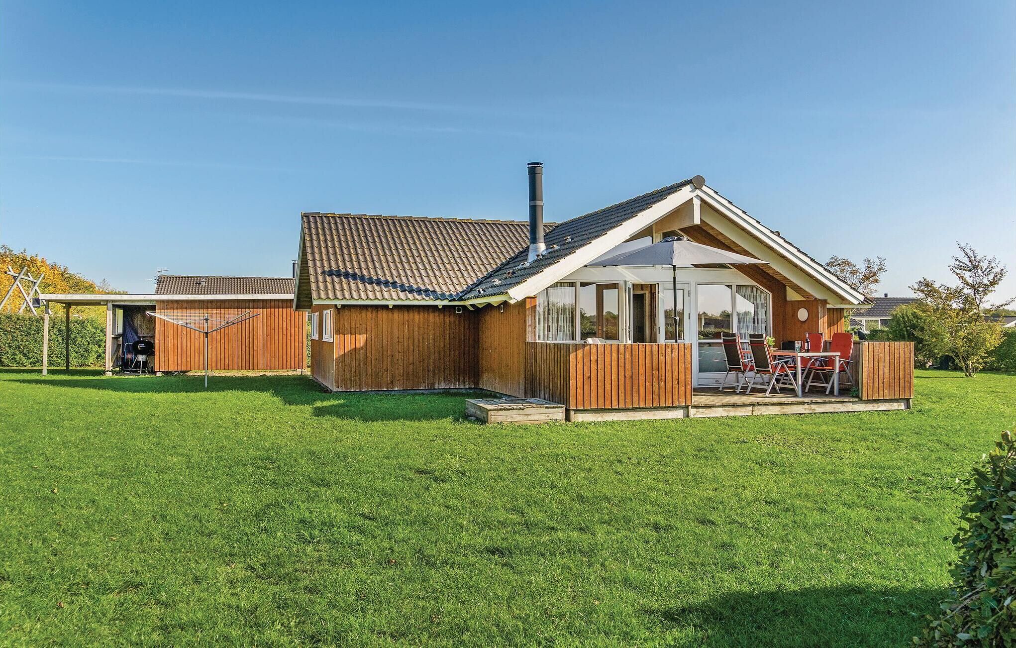 A wooden house with a tiled roof, a chimney, and a patio with outdoor furniture.