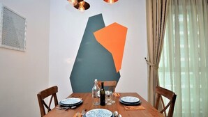 A dining table set with plates, cutlery, and glasses, with a geometric wall art piece above it.