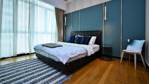 A modern bedroom with a large bed, a small side table, and a chair.