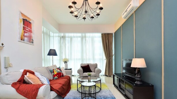 A modern living room with a sofa, two armchairs, a coffee table, a TV, and a chandelier.