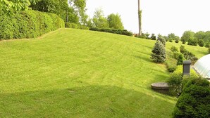 A well-maintained grassy slope with a stone structure and a glass greenhouse. - Comfortable house in Bohemian Paradise with swimming pool, internet (Turnov)