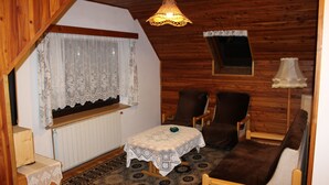 A cozy room with wooden walls, a small table with a lace tablecloth, two chairs, a sofa, and a hanging light fixture. - Comfortable house in Bohemian Paradise with swimming pool, internet (Turnov)