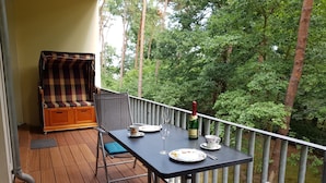 Ein Balkon mit einem Tisch für zwei Personen, einem Stuhl und einer Couch.