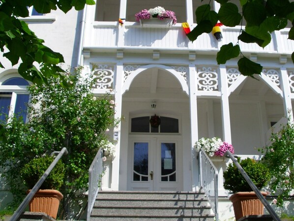 A white building with a front porch, steps, and a door.