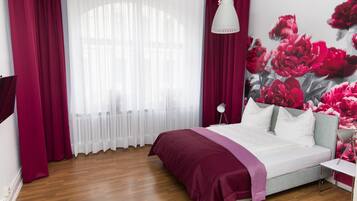 Ein Schlafzimmer mit Bett, Nachttisch, Lampe und einem Fenster mit Vorhängen.