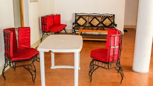 A dining area with a white table and four red chairs, a wooden bench, and a decorative wall panel. - Ibex Guest House (Leh)
