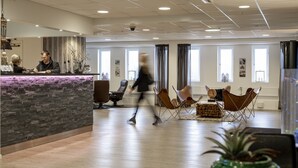 Un hall d’entrée spacieux avec un comptoir de réception, un espace salon et de grandes fenêtres.