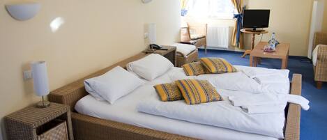A hotel room with a large bed, a television, a chair, and a small table.