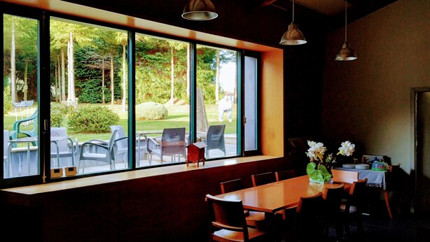 A dining area with a large window overlooking a garden. There are several chairs and a table set up for dining. - Casa Garea (Arzua)