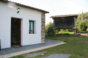 Un bâtiment blanc avec une façade en pierre, une porte en bois et une fenêtre ornée de volets verts.