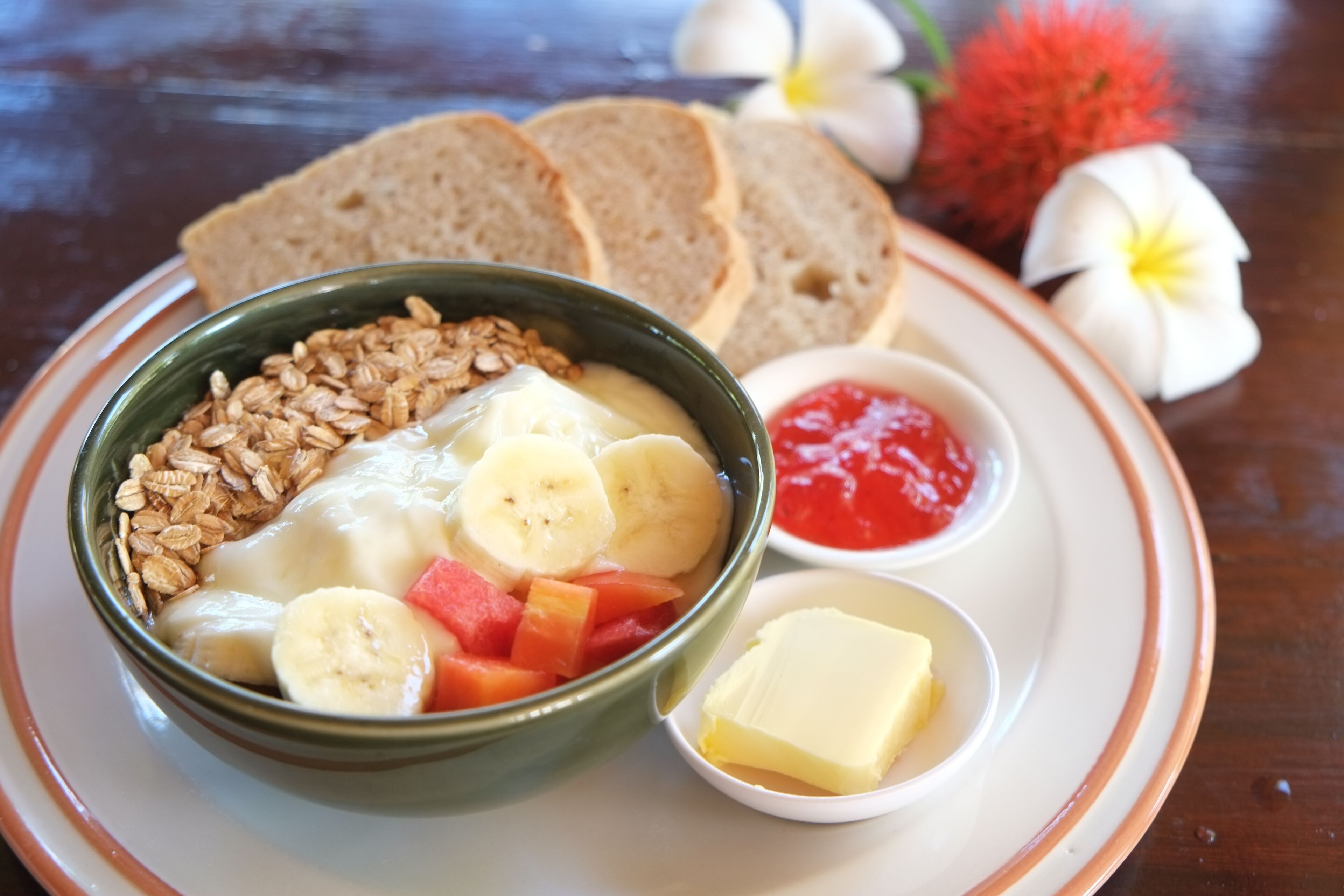 A meal consisting of oatmeal with bananas and strawberries, toast, and butter.