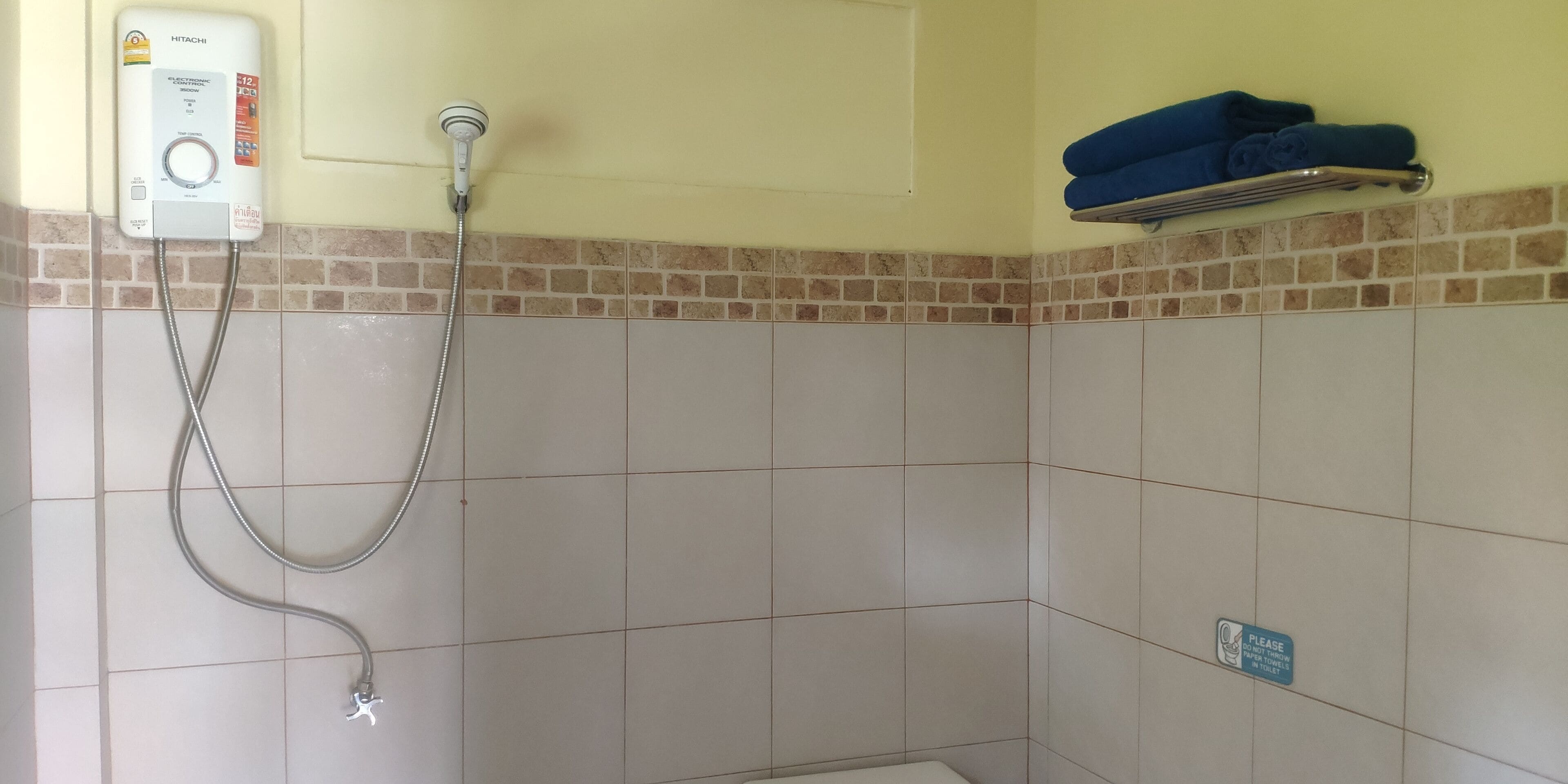A bathroom with a shower, a towel rack, and a sign on the wall.