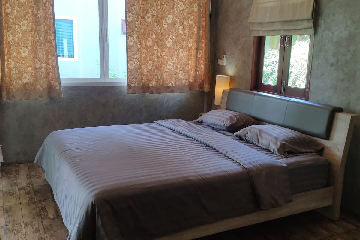 Un dormitorio con cama, cortinas, una ventana y una lámpara.