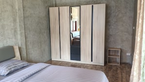 Une chambre à coucher avec un lit, une armoire et une petite étagère en bois.
