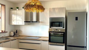 A modern kitchen with a central island, stainless steel appliances, and a unique hanging light fixture. - New villa with swimming pool, magnificent view of the caribbean sea, 1 'from the beach (Les Anses-d'Arlet)