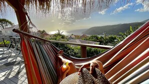 A hammock with a woven bag, a glass of drink, and a view of a coastal landscape. - New villa with swimming pool, magnificent view of the caribbean sea, 1 'from the beach (Les Anses-d'Arlet)
