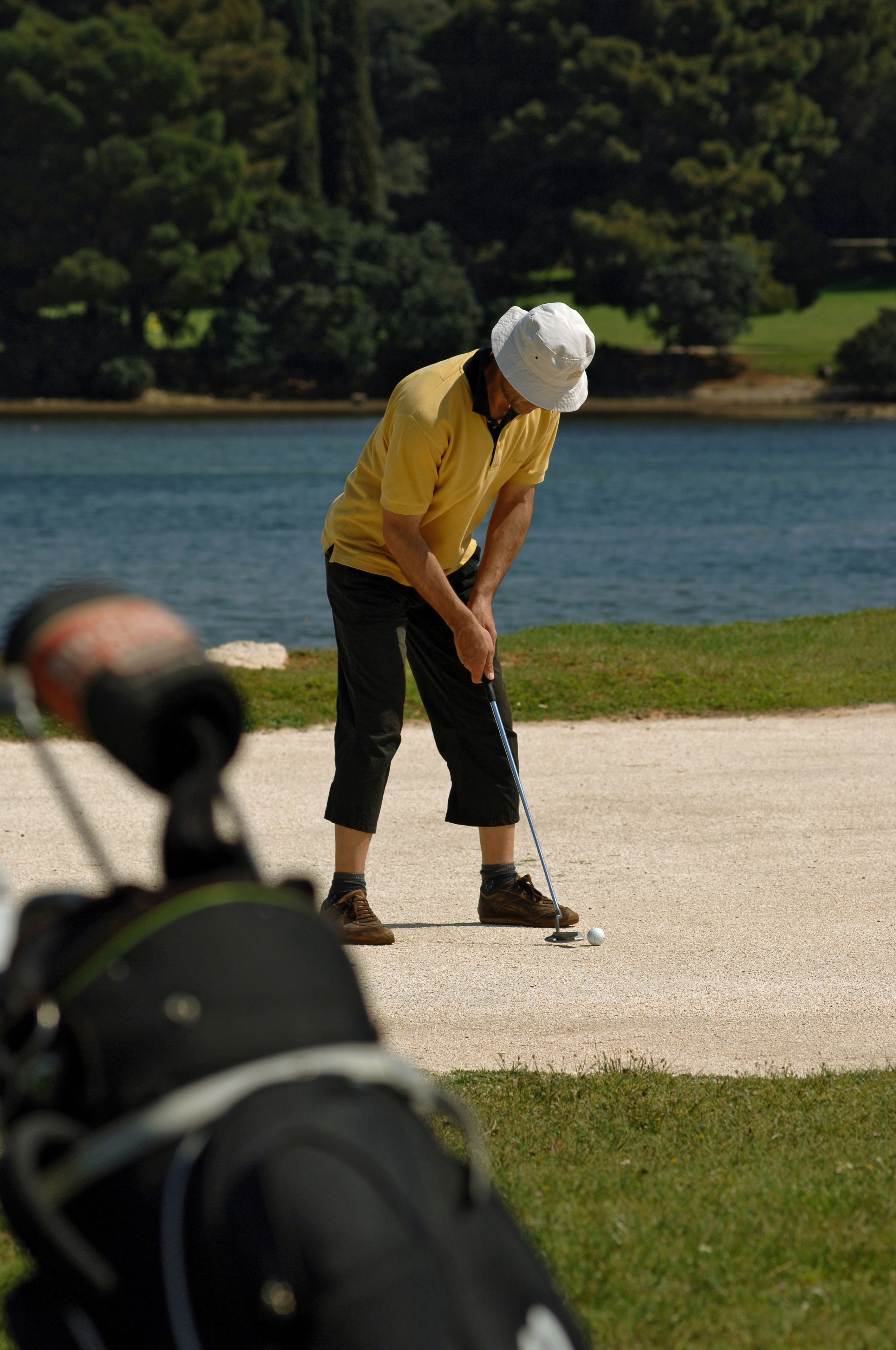 Una persona jugando golf en un campo con un lago al fondo.