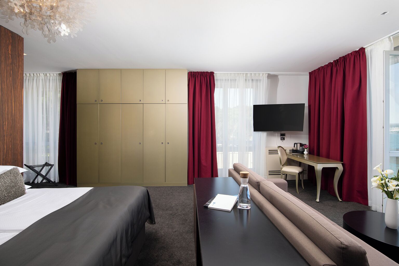 Una habitación de hotel con cama, sofá, escritorio, televisor y armario.
