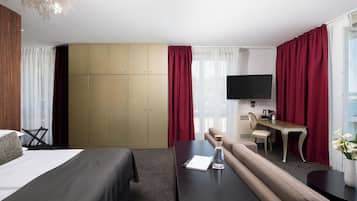 Una habitación de hotel con cama, sofá, escritorio, televisor y armario.
