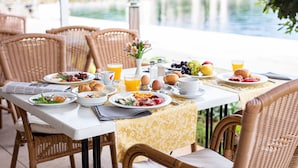 A breakfast table set with plates of food, drinks, and a newspaper. - Brijuni Hotel Istra (Pula)
