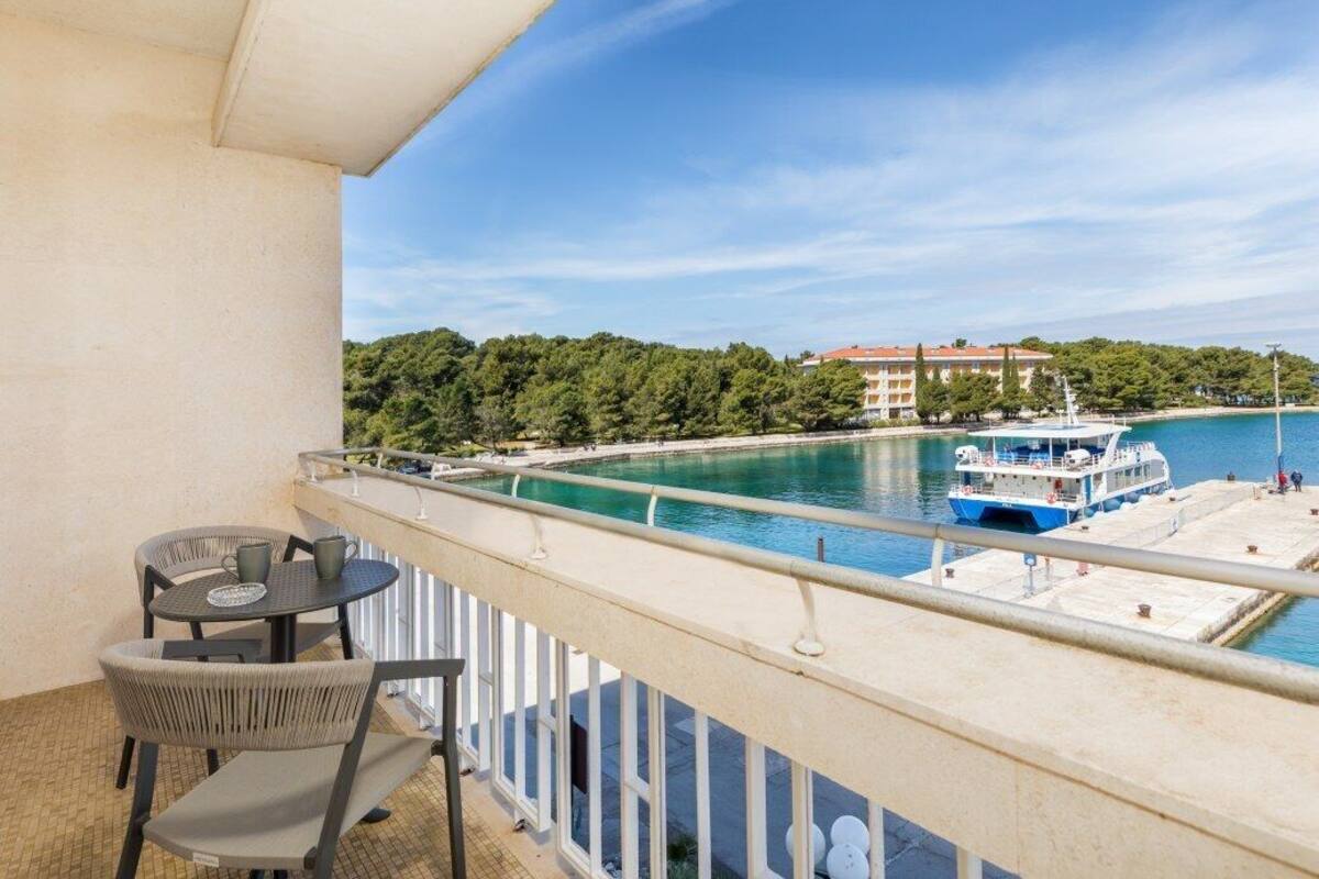 A balcony with a view of a body of water, a boat, and a building in the background.