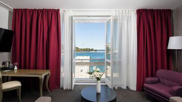 Une chambre d’hôtel avec un balcon, une télévision, une table à manger, un canapé et une table basse.