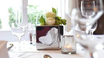 A table set with wine glasses, a candle, and a decorative vase with flowers.