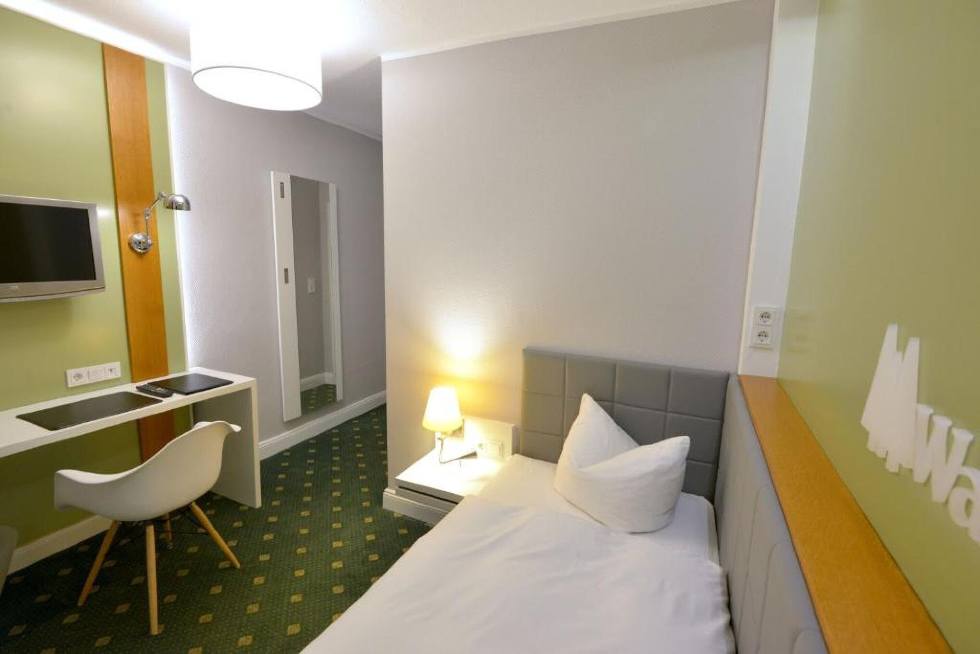 Une chambre d’hôtel comprenant un lit, un bureau avec une chaise, une télévision et une douche.