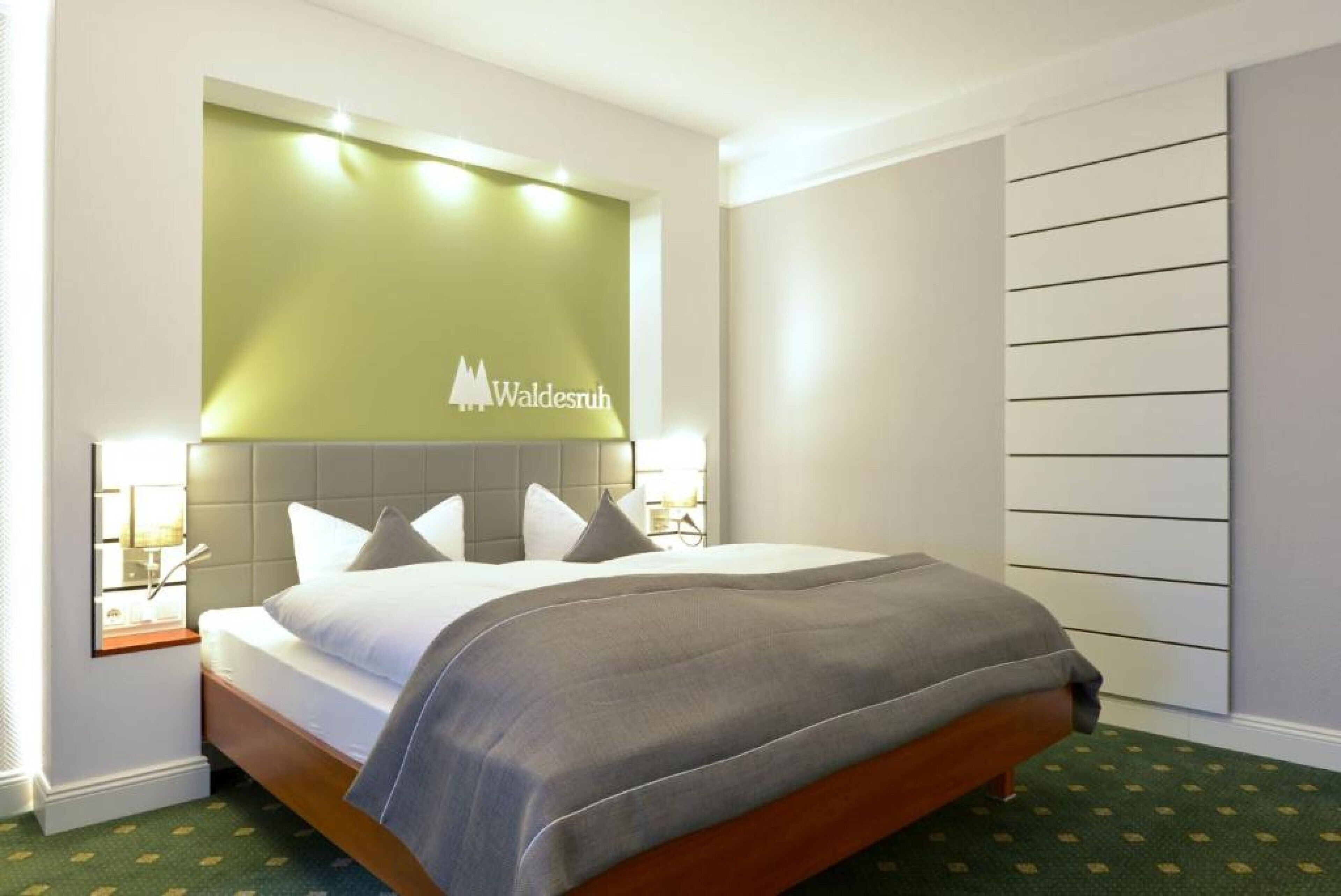 A hotel room with a bed, a headboard with a logo, bedside lamps, and a patterned carpet.